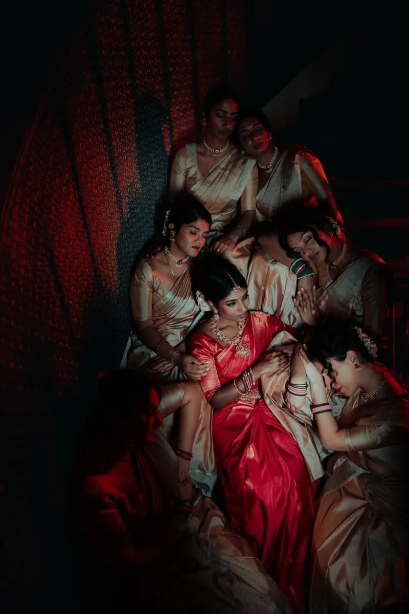 Bridesmaids in matching saris, gathered around the bride.